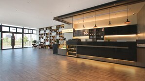 A modern reception area with a wooden floor, a reception desk, and a bookshelf filled with books. - Hanting Hotel (Zhenjiang)