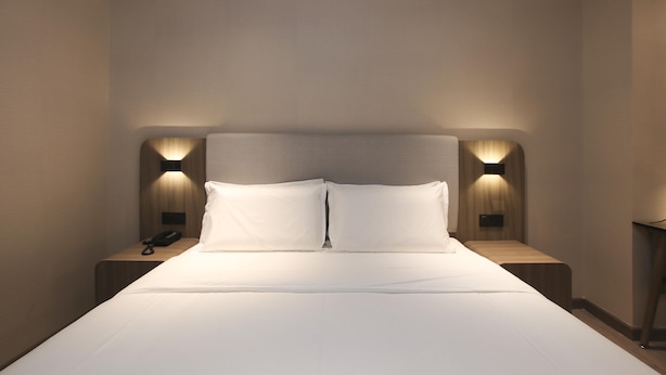 A hotel room with a bed, bedside tables, and wall-mounted lamps. - Hanting Hotel (Zhenjiang)