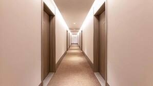 A long, narrow hotel corridor with wooden doors on both sides and a carpeted floor. - Hanting Hotel (Zhenjiang)