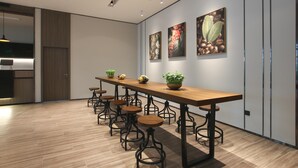 A modern dining area with a long wooden table, multiple bar stools, and wall-mounted artwork. - Hanting Hotel (Zhenjiang)
