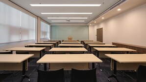 A conference room with multiple tables and chairs, a projector screen, and a large window. - Hanting Hotel (Zhenjiang)