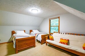 A room with two wooden beds, a sofa, a window, and a ceiling light.