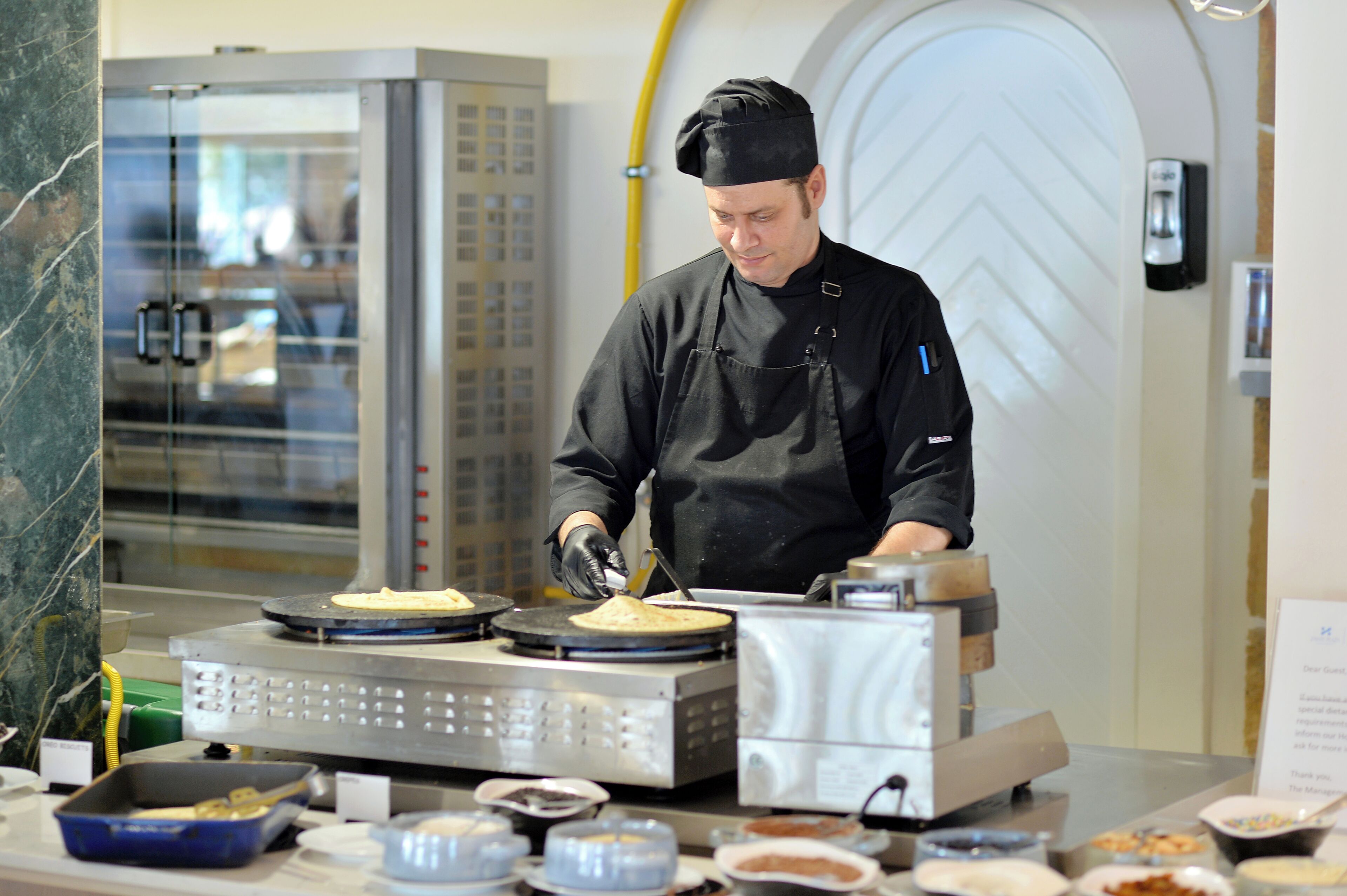 Un cocinero preparando comida en una cocina con un horno grande y diversos utensilios de cocina.