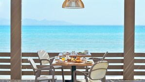 A dining table with chairs and a view of the sea.