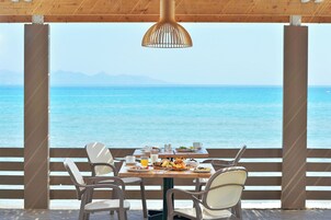 A dining table with chairs and a view of the sea.
