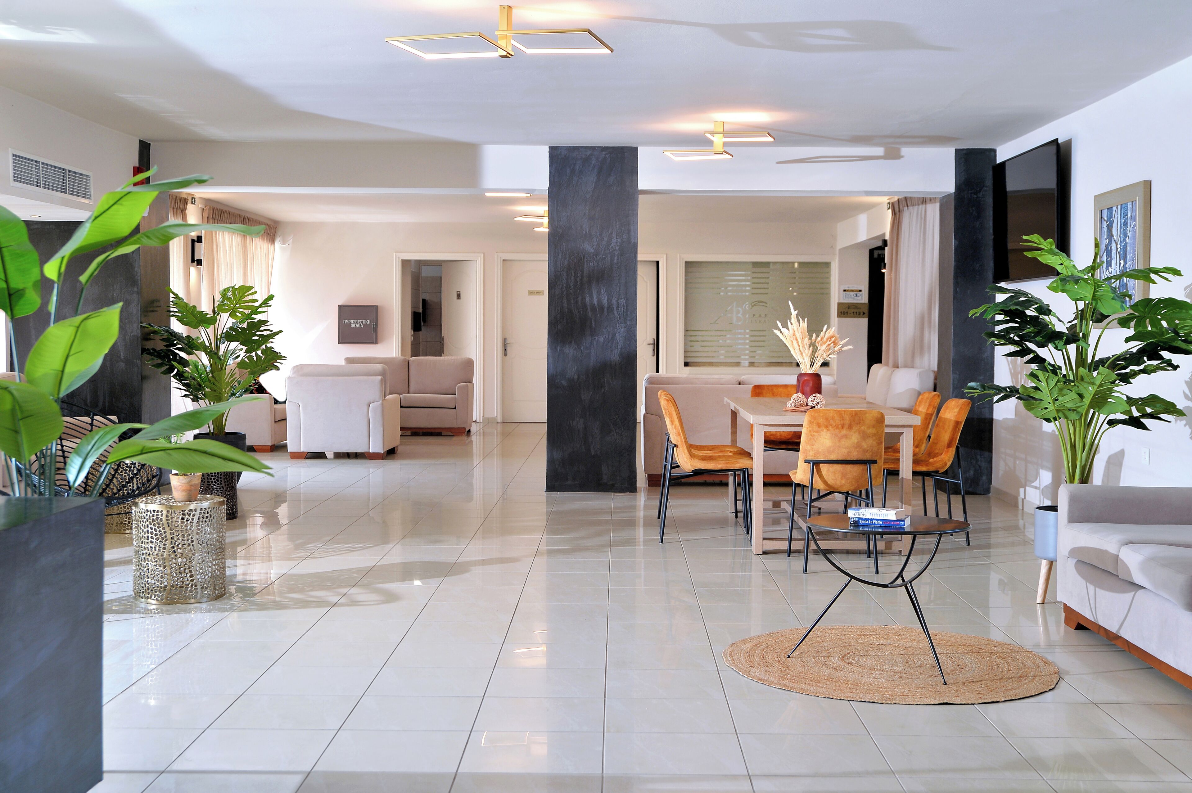 A modern living room with a dining area, featuring a large black accent wall, a sofa, a coffee table, and potted plants.