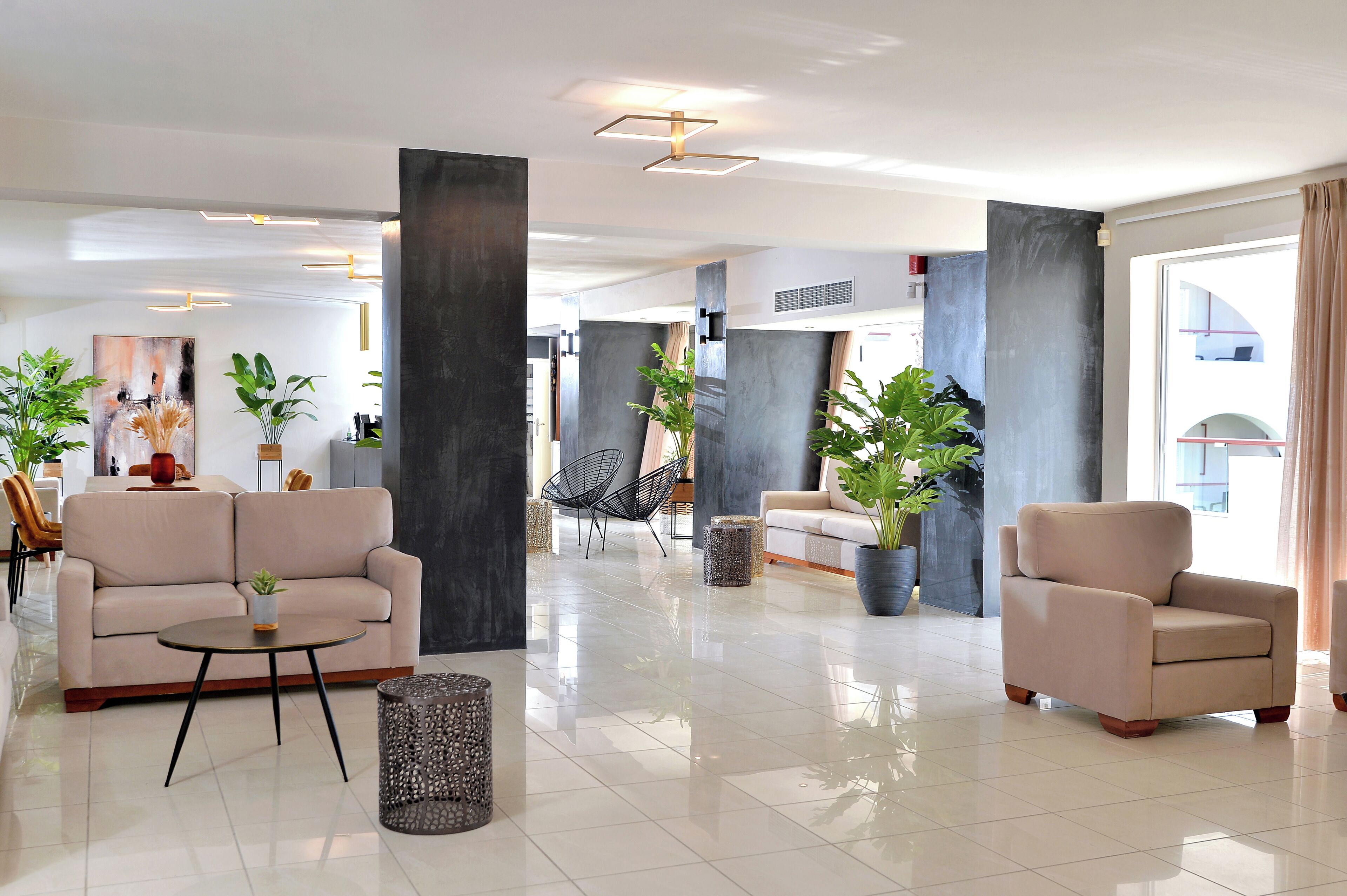 A modern lobby with a sofa, armchair, and potted plants.