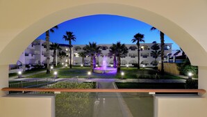 A hotel courtyard with a fountain, palm trees, and a pool.