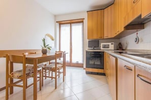 Une cuisine avec des meubles de rangement en bois, un four à micro-ondes, un four traditionnel et une table à manger avec des chaises.