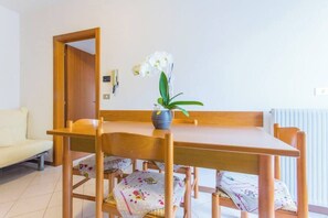 Un coin repas avec une table et des chaises en bois, un vase rempli de fleurs blanches et un radiateur blanc.