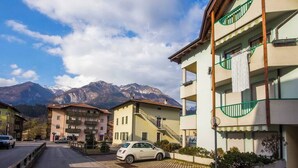 A street view with buildings, a parked car, and mountains in the background.