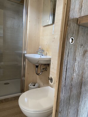 A bathroom with a white sink, a toilet, and a shower. - tinyhouseHotel Beilngries (Beilngries)