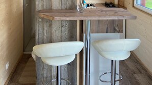 A compact kitchen with a wooden countertop, a built-in TV, and two white bar stools.