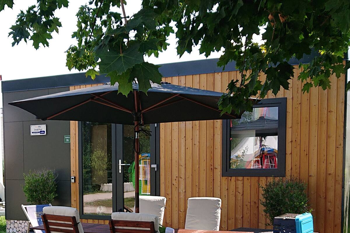 Un patio al aire libre con mobiliario de madera, una mesa y una parrilla.