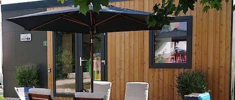An outdoor patio with wooden furniture, a table, and a grill.