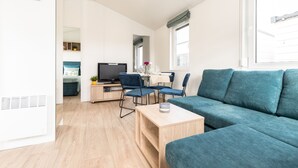 A modern living room with a teal sofa, a wooden coffee table, and a TV.