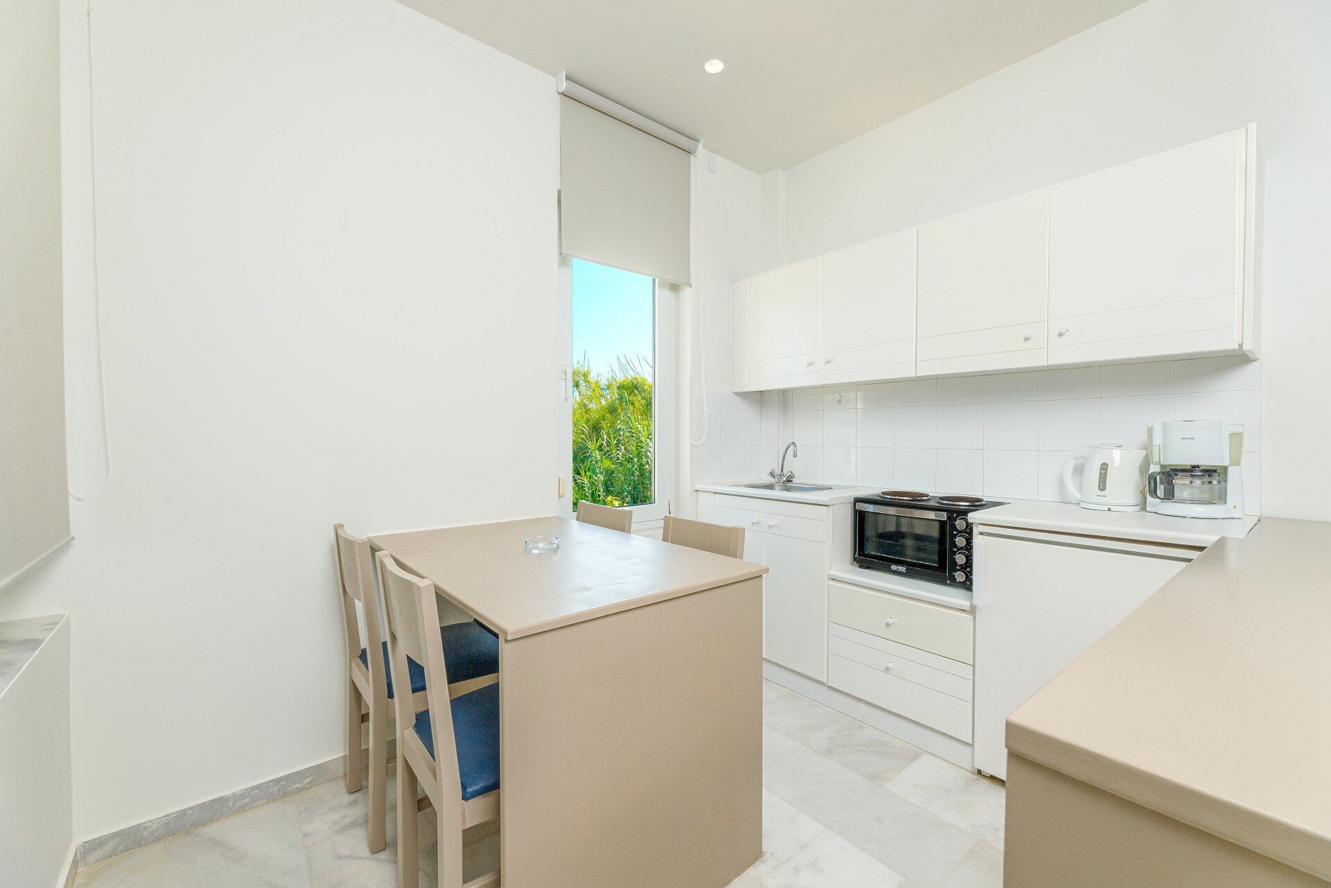 A modern kitchen with white cabinets, a built-in oven, and a coffee machine.