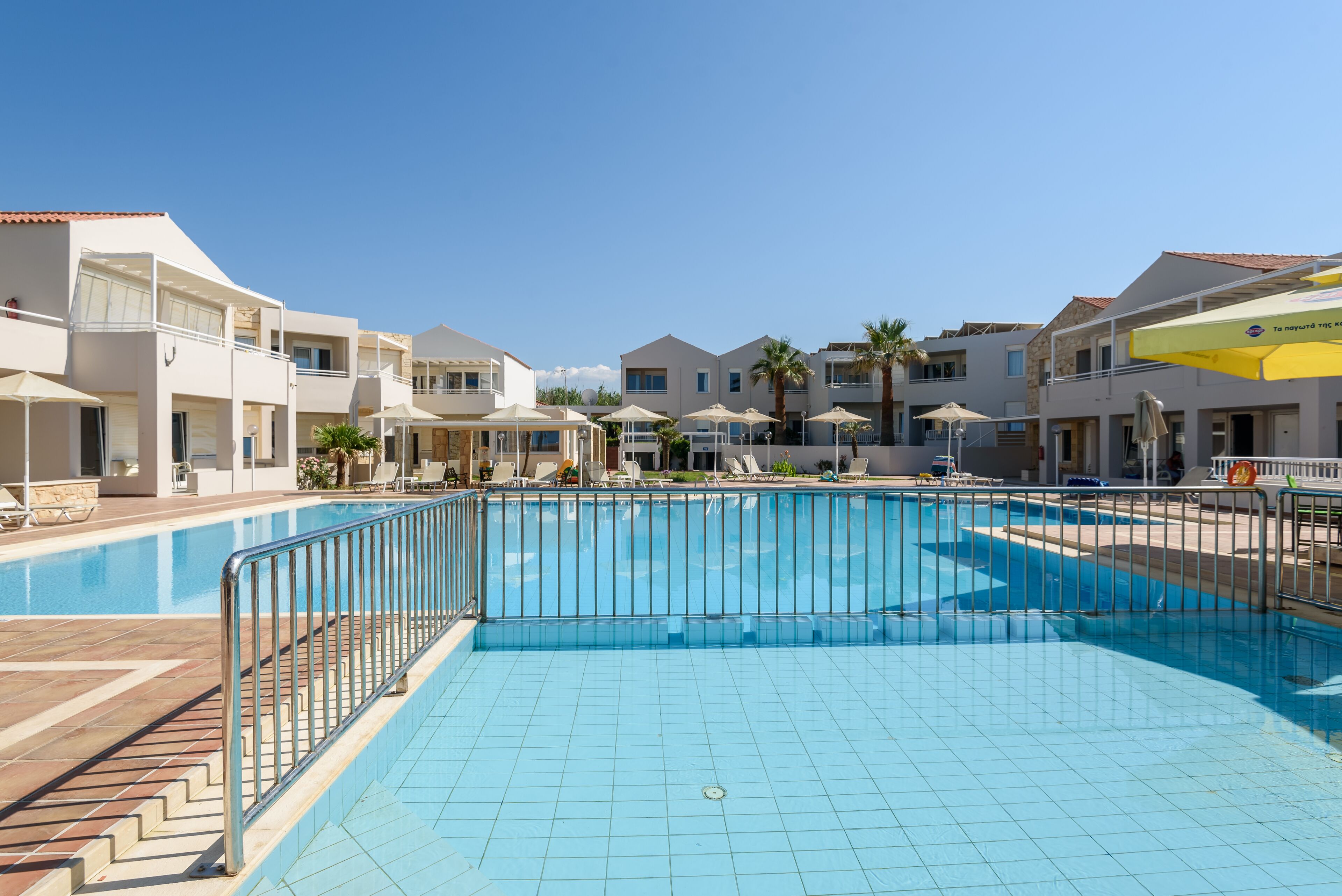 Une piscine entourée de bâtiments modernes dotés de balcons et de chaises longues.