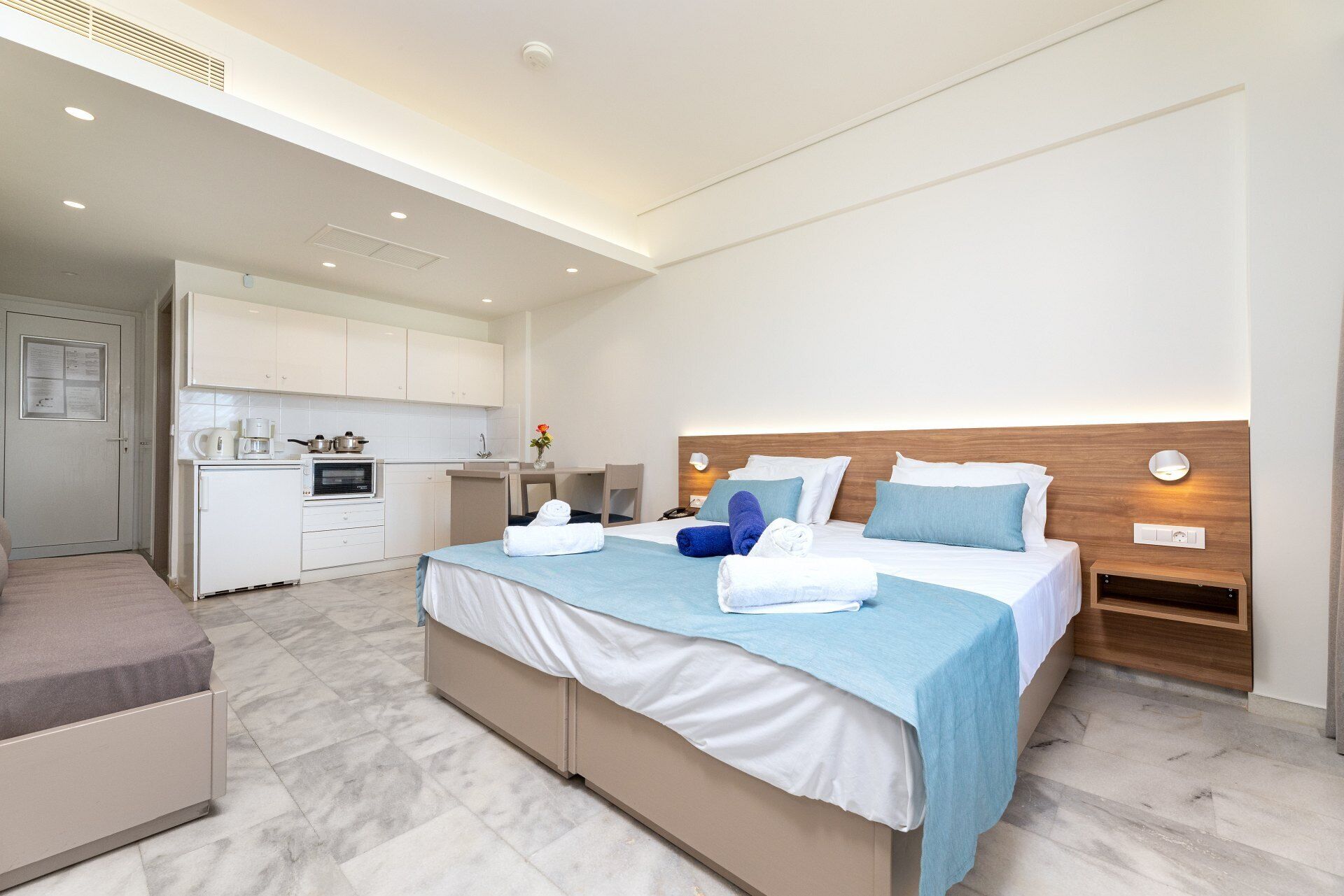 Una habitación de hotel moderna con cama, mesita de noche y kitchenette.