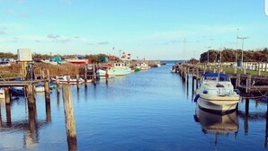 Ein Yachthafen mit vertäuten Booten an hölzernen Stegen, ruhigem Wasser und blauem Himmel.