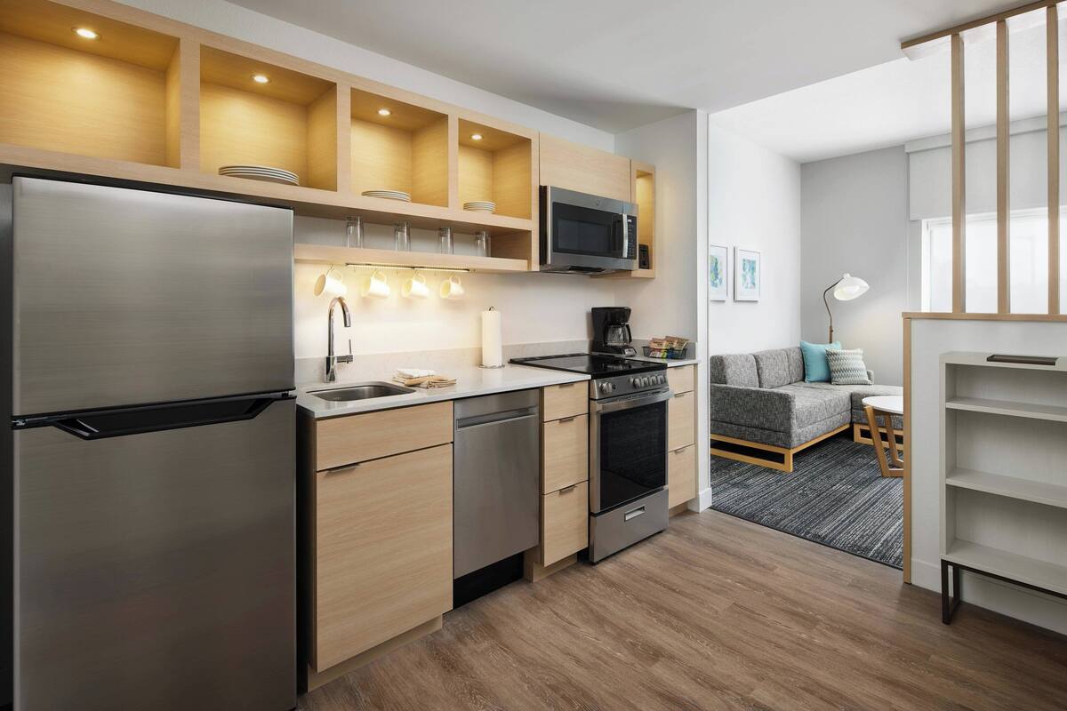 A modern kitchen with stainless steel appliances, wooden cabinets, and a built-in microwave.