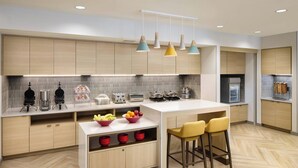 Une cuisine moderne avec des meubles en bois, un plan de travail blanc et un îlot central doté de tabourets.