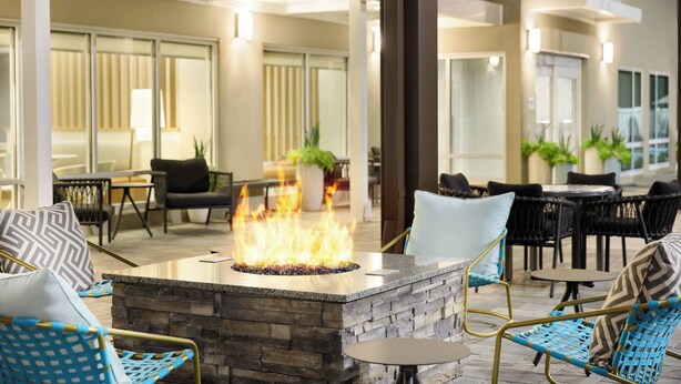 Un espace extérieur aménagé avec un foyer, des fauteuils en osier et une cheminée en pierre.