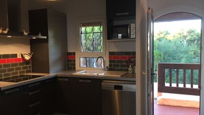 A modern kitchen with a dishwasher, a window with a view of greenery, and a door leading to an outdoor area. - MAGNIFICENT SEA VIEW 🌊  (Sausset-les-Pins)