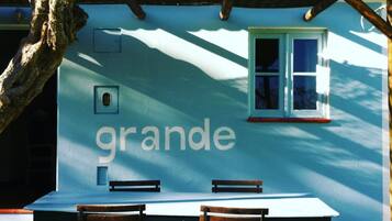 A dining table with chairs, a window, and a wall with the word "grande" written on it.