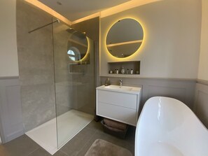 Un bagno moderno con doccia vetrata, un lavabo con specchio e una vasca da bagno.
