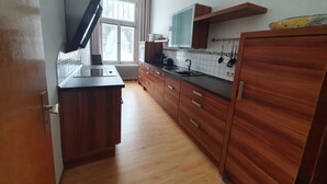 A modern kitchen with wooden cabinets, a black countertop, and a window providing natural light.