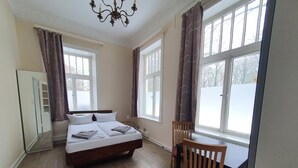 A bedroom with a bed, a chair, and large windows.