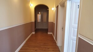 A hallway with wooden flooring, cream walls, and white trim. There is a door with the number '1' on it.