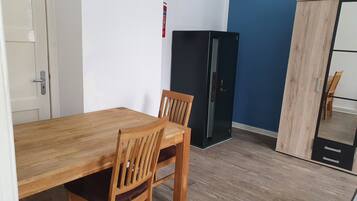 A room with a wooden dining table and chairs, a black cabinet, and a wardrobe.
