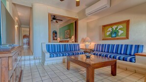 Ein Wohnzimmer mit einem gestreiften Sofa, einem Holztisch und einem Fliesenboden.