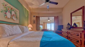 Ein Schlafzimmer mit einem Bett, einem Schminktisch, einem Deckenventilator und einem Fenster mit Blick.