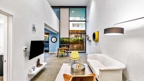 Un interior moderno con un sofá, sillas, un televisor y un comedor.