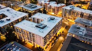 Un edificio de varios pisos con techo plano, rodeado de otros edificios.