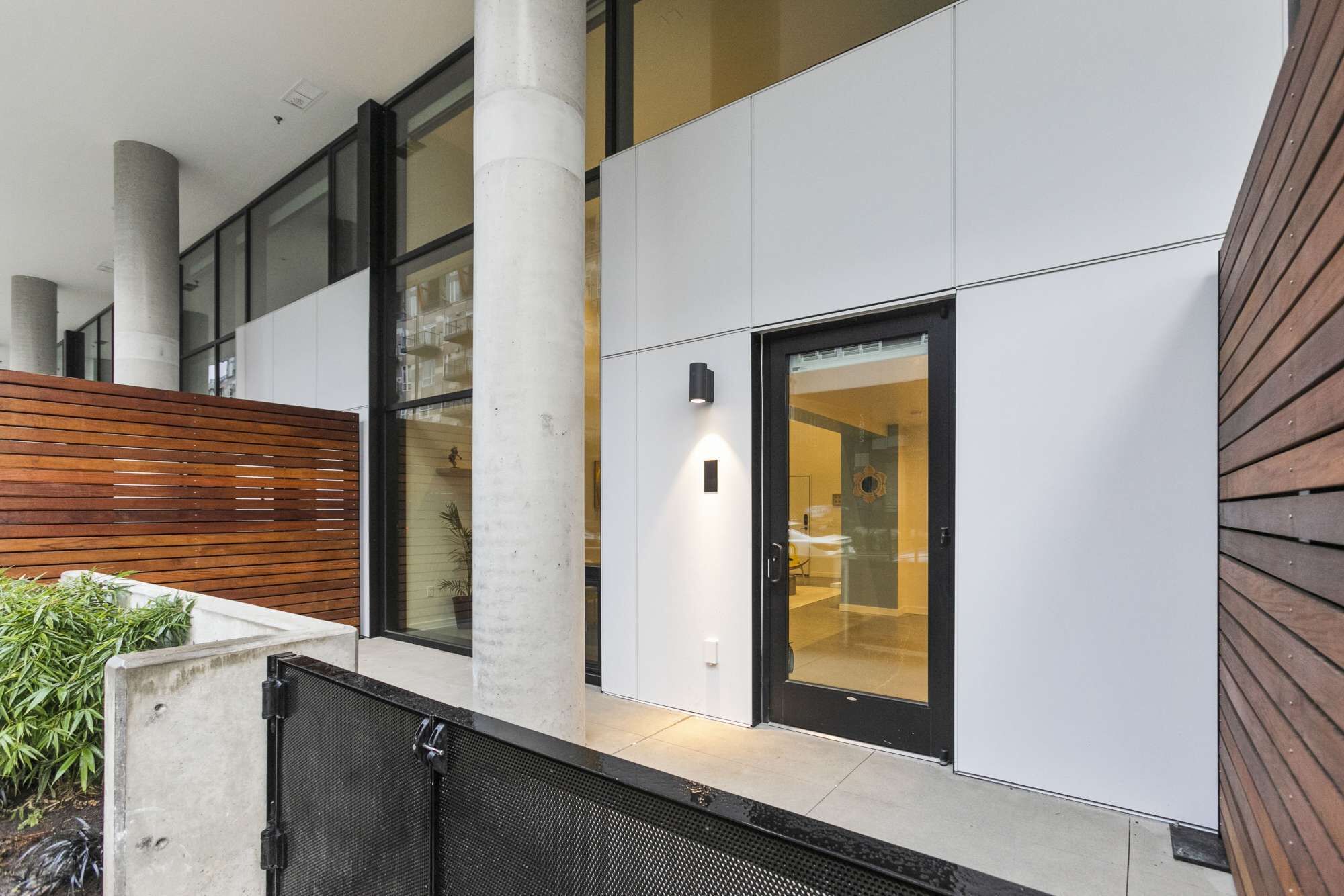 A modern building with large windows, a wooden slatted wall, and a glass door.