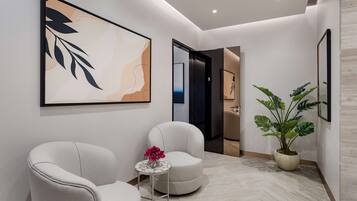 A modern hallway with two armchairs, a small table with flowers, and a large abstract painting on the wall.