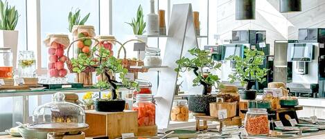 A modern buffet setup with various food items and decorative plants.