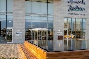 Un hôtel doté d’une façade moderne, de grandes fenêtres en verre et d’une terrasse en bois.