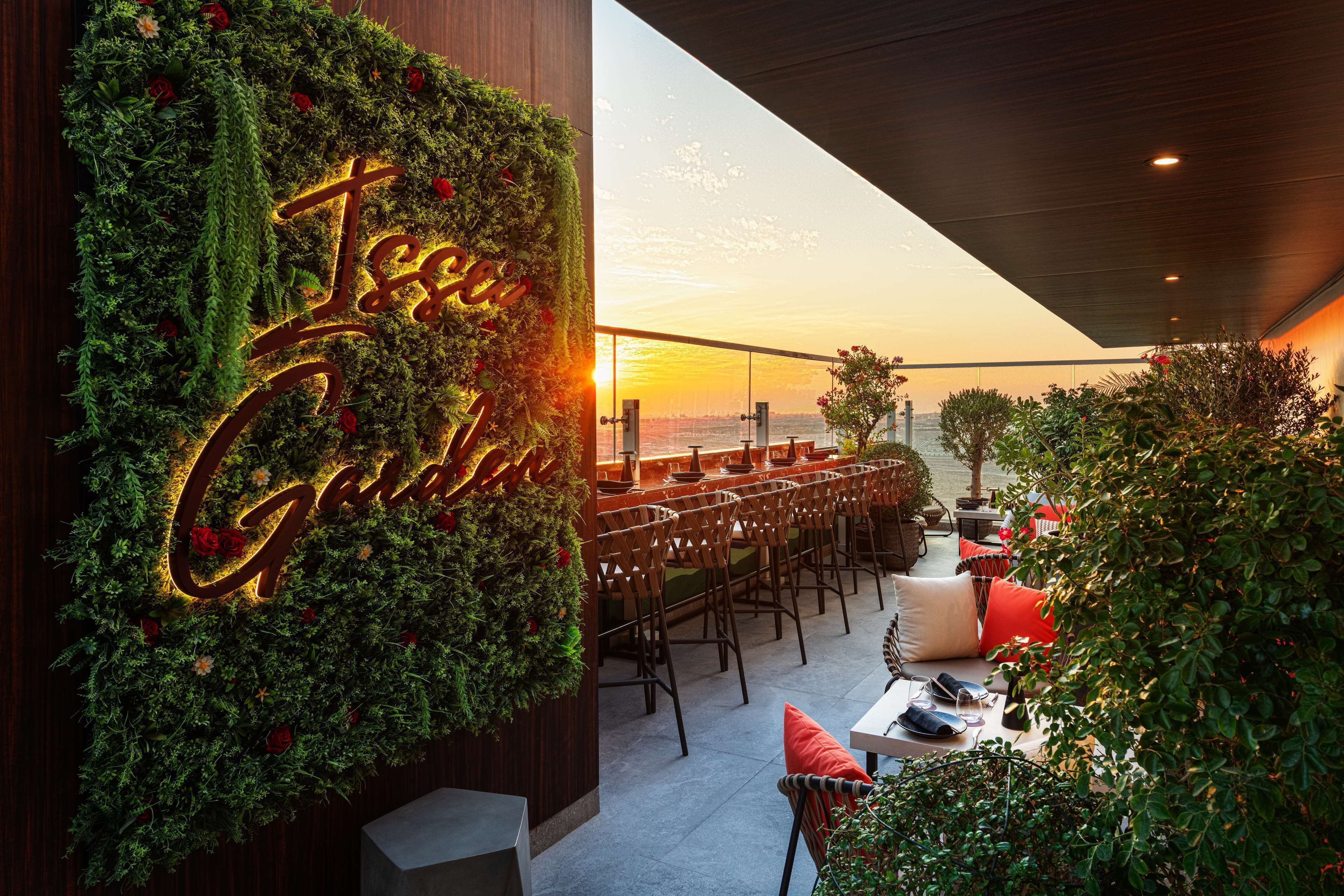 Um restaurante com parede verde e letreiro de neon com a inscrição 'Tee Garden'.