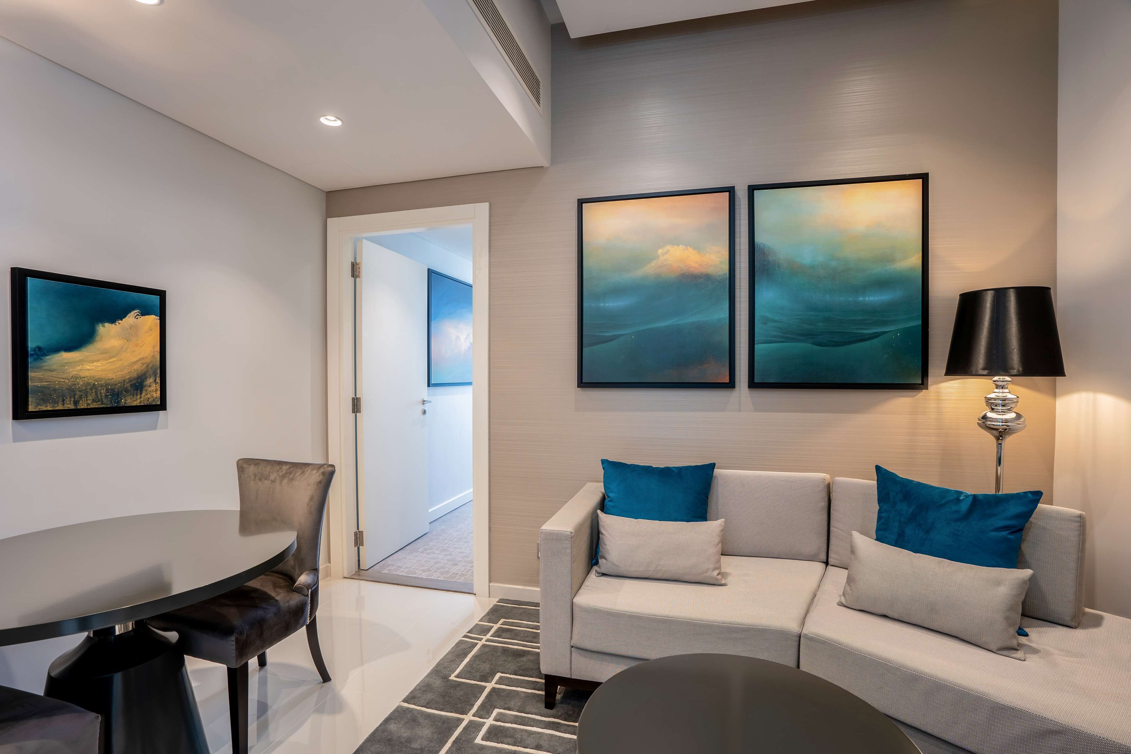 A modern living room with a sofa, a dining table, and artwork on the wall.