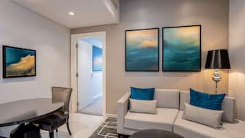 A modern living room with a sofa, a dining table, and artwork on the wall.