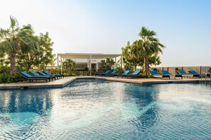 Une piscine avec des chaises longues et des palmiers.