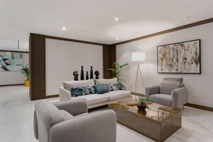 A modern living room with a sofa, armchairs, a coffee table, and decorative items.