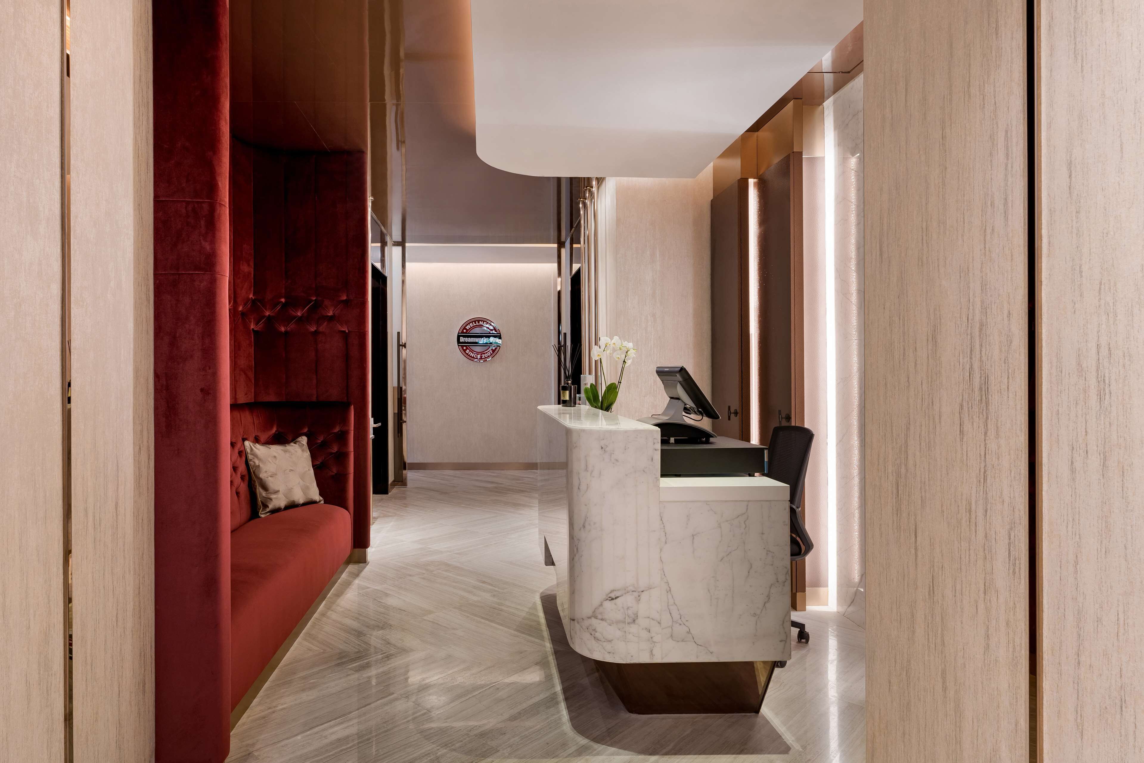 Un moderno vestíbulo de hotel con un mostrador de recepción de mármol, un sofá rojo acolchado y un diseño minimalista.