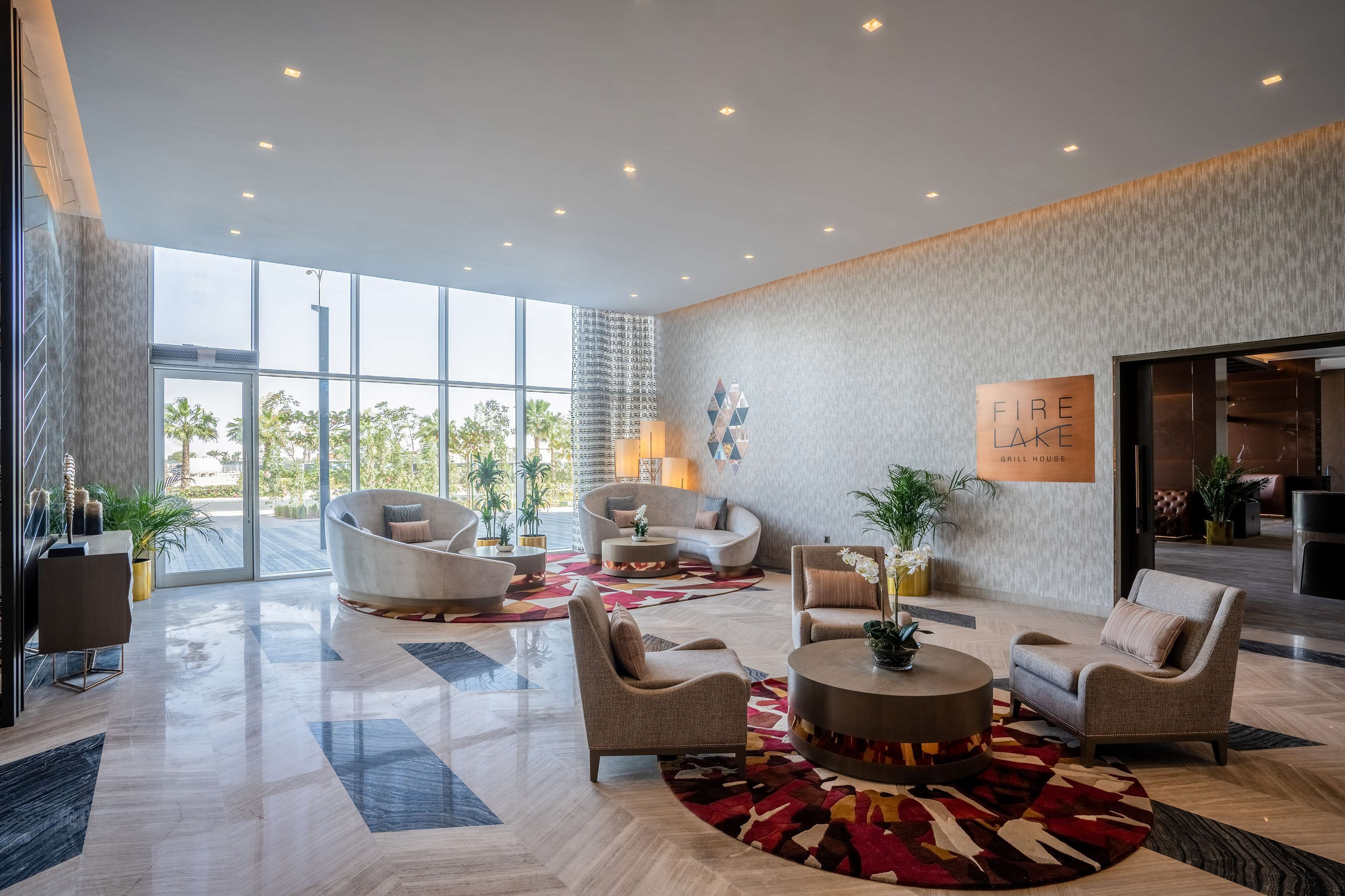 A spacious lobby with modern furniture, large windows, and a sign for a grill house.