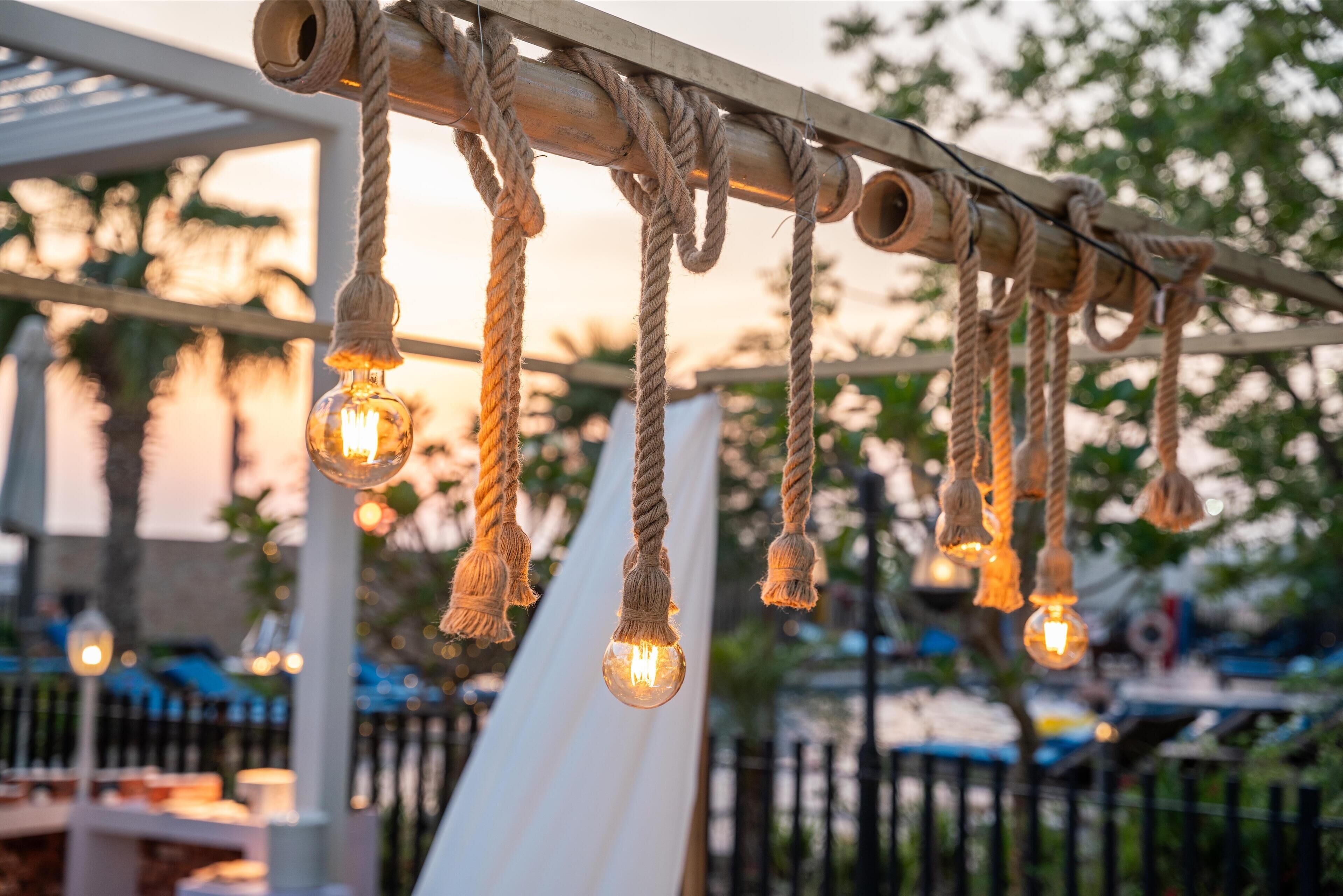 A rope light fixture with bulbs, a white tent, and a metal fence in the background.